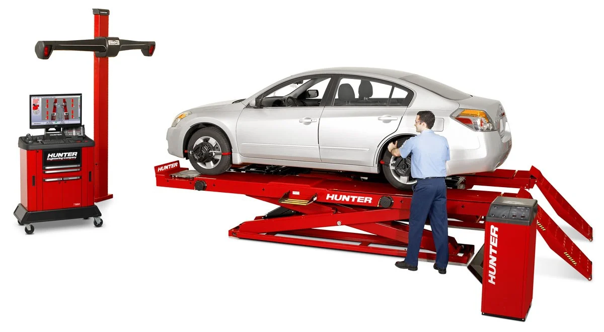 Car maintenance representative performing a wheel alignment on a white four-door sedan elevated on a Hunter HawkEye Elite®