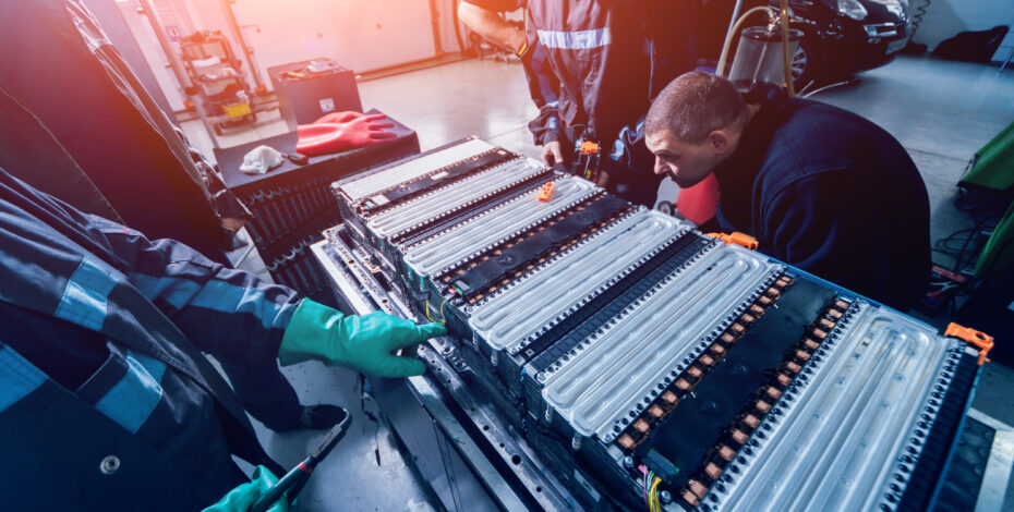 technicians standing next to an electric vehicle battery