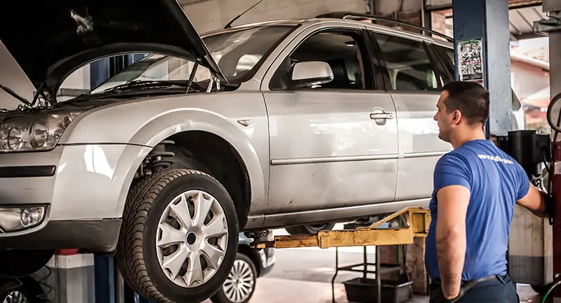 Mechanic using a low-rise automotive lift