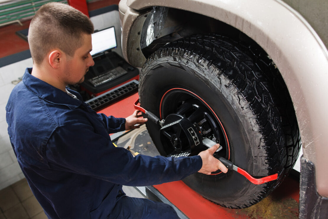 A mechanic putting wheel clamps on a tire before an alignment